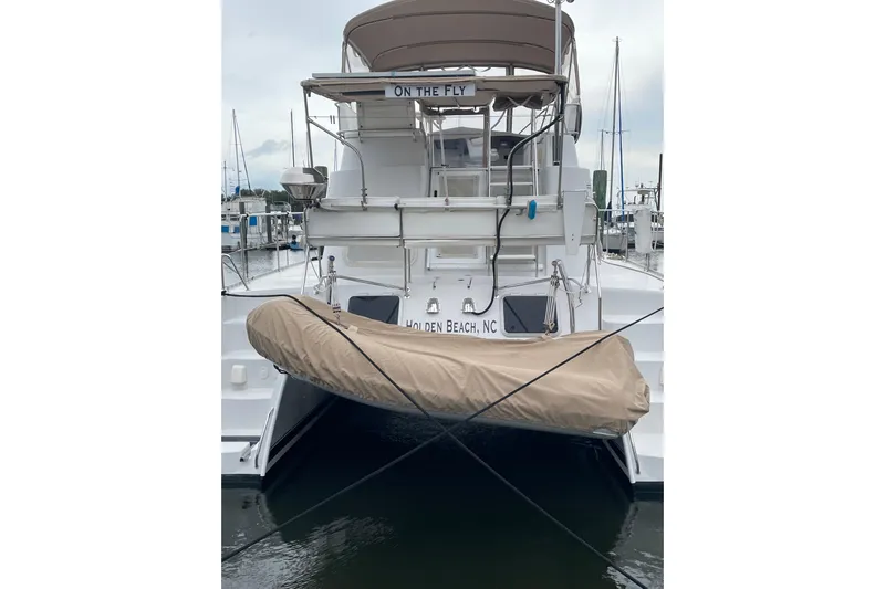 On The Fly Yacht Photos Pics 2005 PDQ 34 Power Catamaran docked at marina, rear view with covered dinghy.