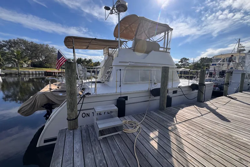 On The Fly Yacht Photos Pics 2005 PDQ 34 Power Catamaran docked, featuring a sun canopy and American flag.