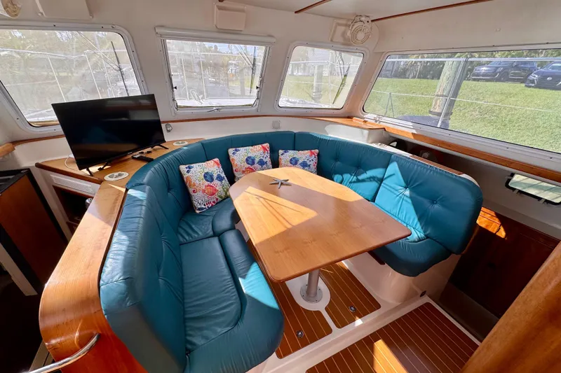 On The Fly Yacht Photos Pics 2005 PDQ 34 Power Catamaran interior with teal seating, wooden table, and TV.