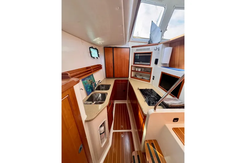 On The Fly Yacht Photos Pics Interior of 2005 PDQ 34 Power Catamaran featuring kitchen with stove, sink, and wooden cabinetry.