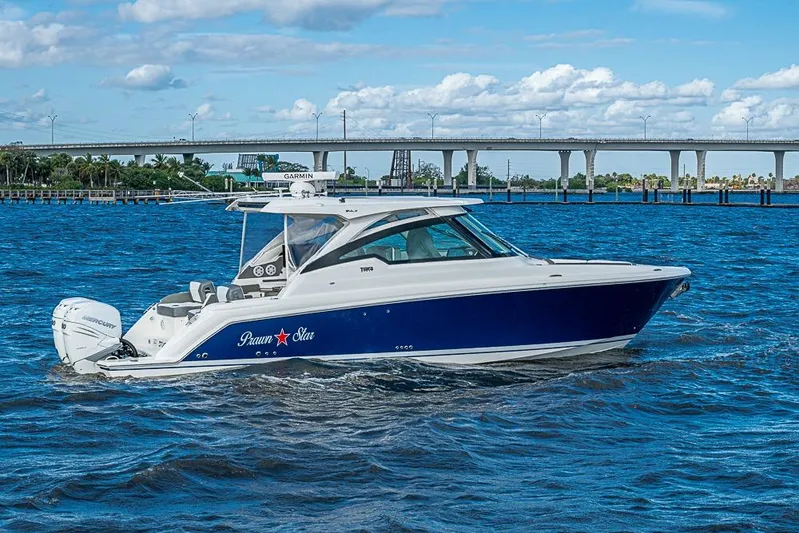 Prawn Star Yacht Photos Pics 2022 Tiara Yachts 34 LX cruising on blue waters near a bridge.