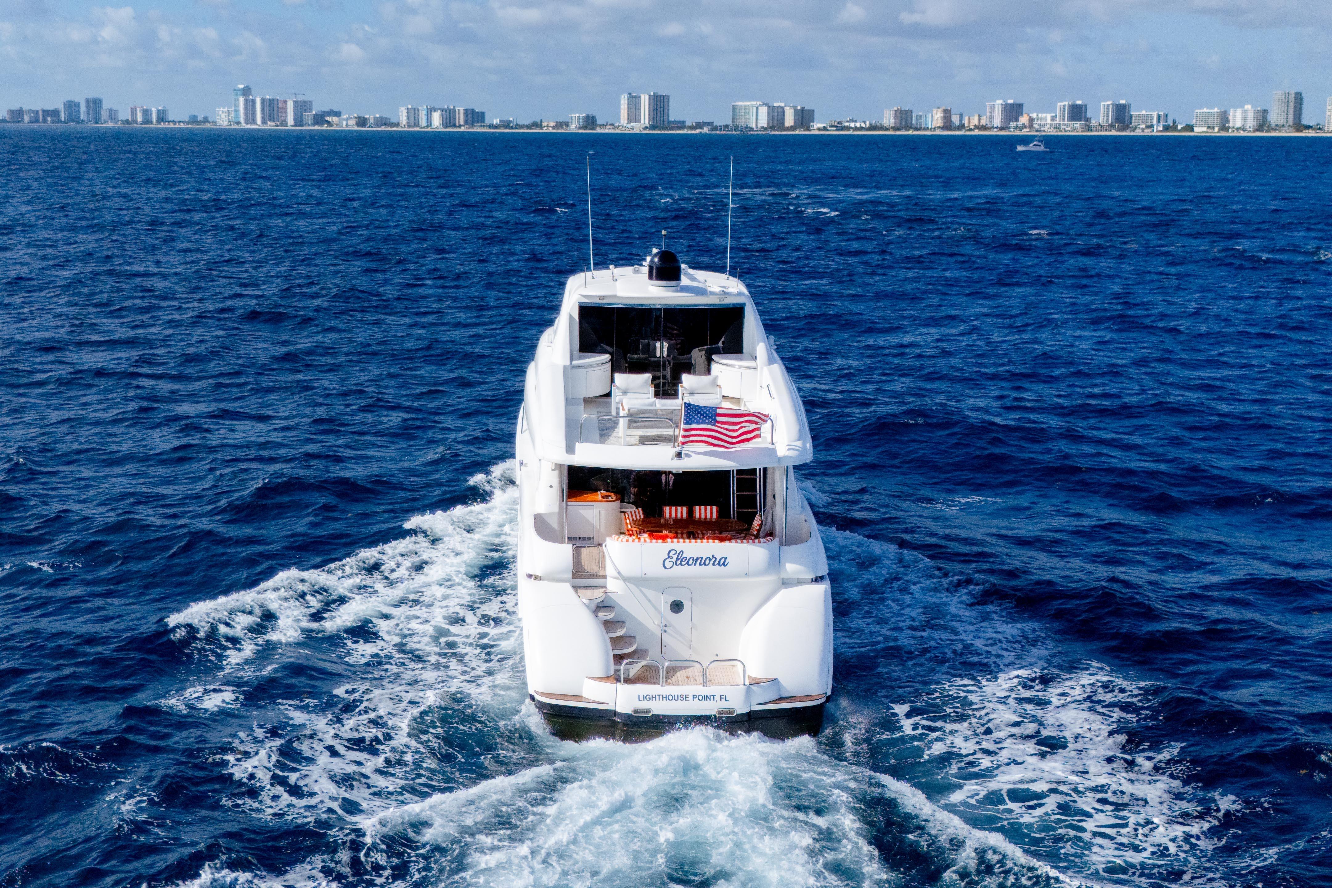 Luxury 2004 Lazzara 80 SL yacht cruising near city skyline on blue ocean.