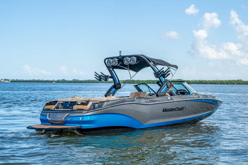  Yacht Photos Pics 2022 MasterCraft X26 boat on calm water under a clear blue sky.
