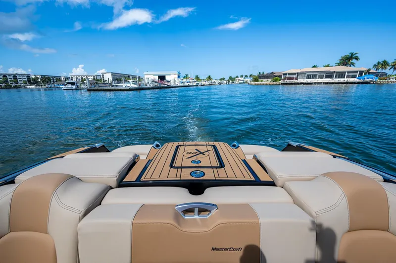  Yacht Photos Pics 2022 MasterCraft X26 boat on water, showcasing luxurious seating and scenic marina view.