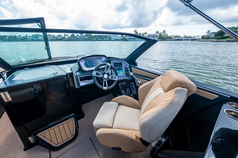  Yacht Photos Pics 2022 MasterCraft X26 boat interior with steering wheel and captain's chair on a lake.