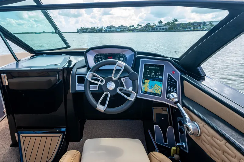  Yacht Photos Pics 2022 MasterCraft X26 boat cockpit with modern steering and digital controls on a lake.