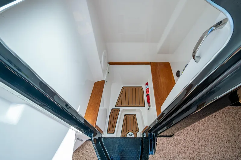  Yacht Photos Pics 2022 MasterCraft X26 boat interior with wooden flooring and fire extinguisher.