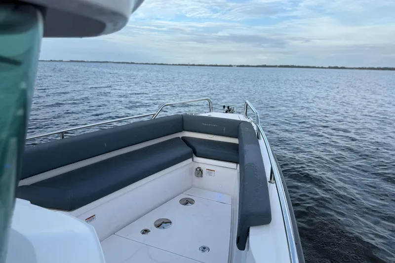  Yacht Photos Pics 2022 Axopar 28 Cabin boat with cushioned seating, on calm water under a cloudy sky.