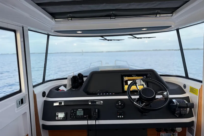  Yacht Photos Pics Interior view of 2022 Axopar 28 Cabin boat cockpit with steering wheel and navigation controls.