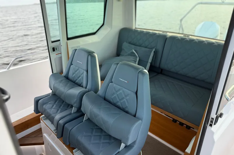  Yacht Photos Pics 2022 Axopar 28 Cabin interior with blue quilted seats and ocean view.