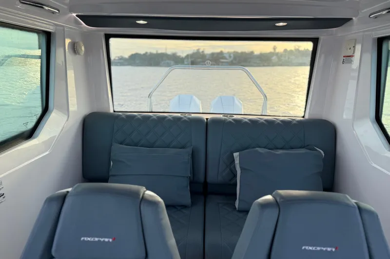  Yacht Photos Pics Interior of 2022 Axopar 28 Cabin boat with cushioned seating and scenic water view.
