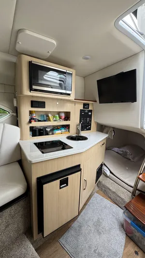  Yacht Photos Pics 2024 Regal 26 XO boat interior with kitchenette, microwave, TV, and storage.