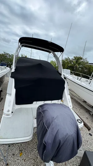  Yacht Photos Pics 2024 Regal 26 XO boat with cover, docked under cloudy skies.