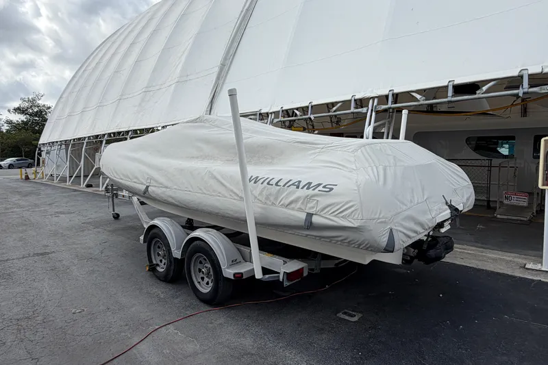  Yacht Photos Pics 2023 Williams Jet Tenders Dieseljet 625 covered on trailer near large tent structure.