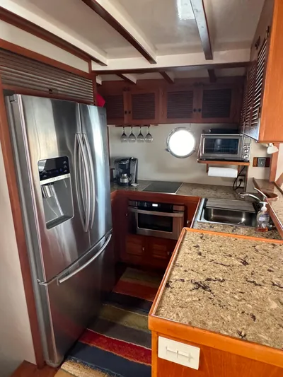 Dyer Need Yacht Photos Pics Compact kitchen in a 1996 Kadey-Krogen 48 yacht with modern appliances and wooden cabinetry.