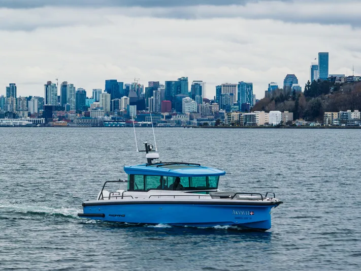 Aqvavit Yacht Photos Pics 2021 Axopar 37xc Wetbar boat cruising with city skyline in the background.