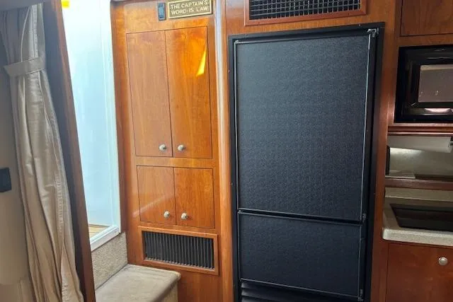  Yacht Photos Pics 2004 Cruisers Yachts 370 Express interior with wood cabinetry and black refrigerator.