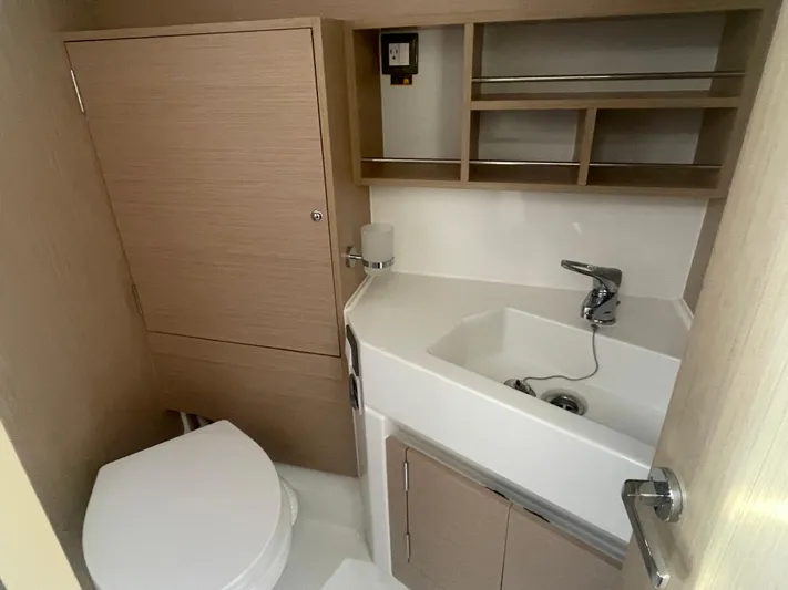 Cutting Edge Yacht Photos Pics 2023 Beneteau Oceanis 34.1 yacht bathroom with modern sink, toilet, and storage shelves.
