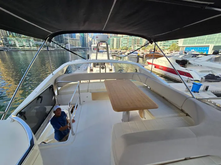  Yacht Photos Pics Flybridge view of 2015 Absolute 56 FLY yacht with seating and table, docked in marina.