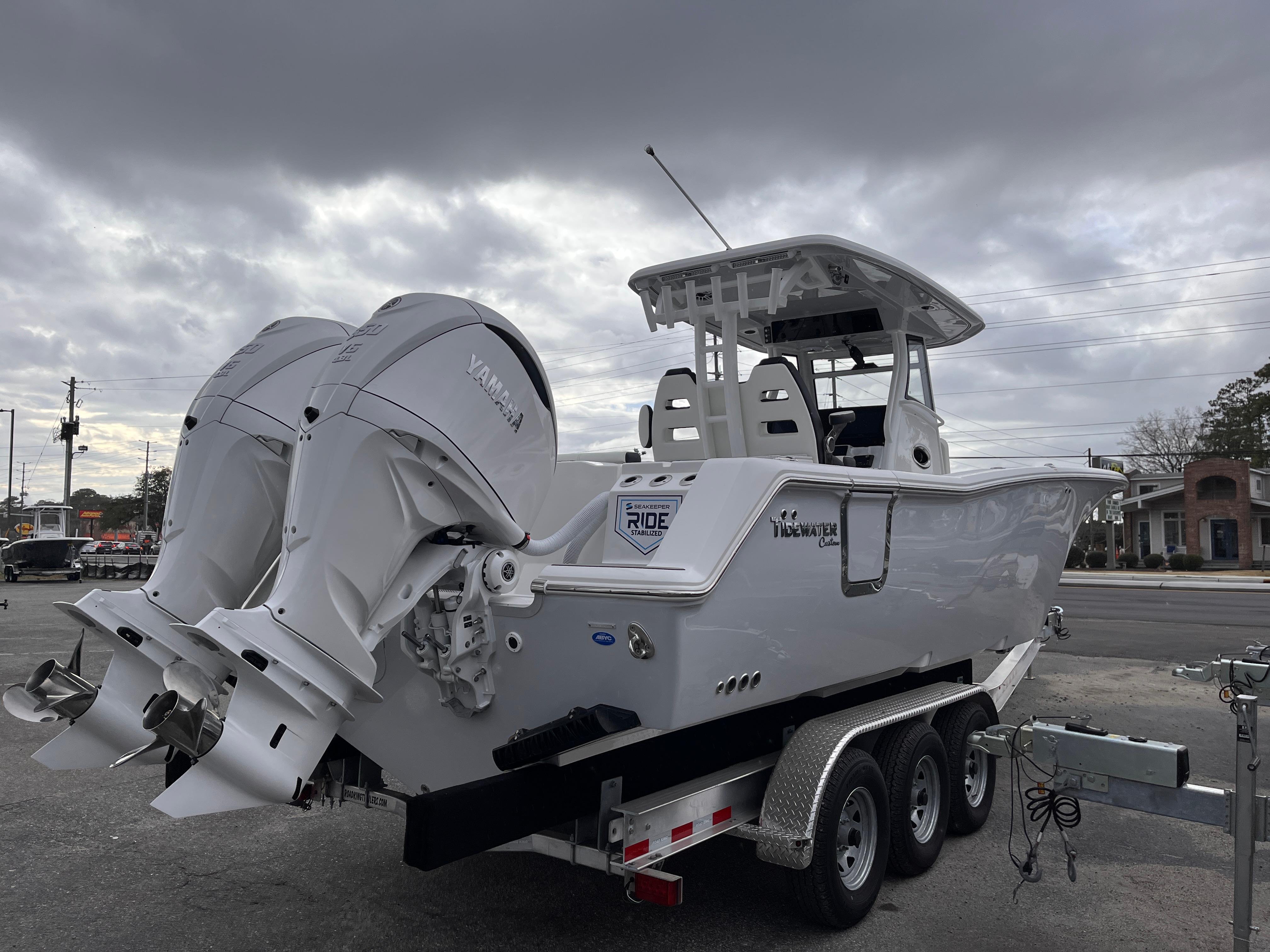 2025 Tidewater 302 CC Adventure boat on trailer, featuring dual engines, under cloudy sky.
