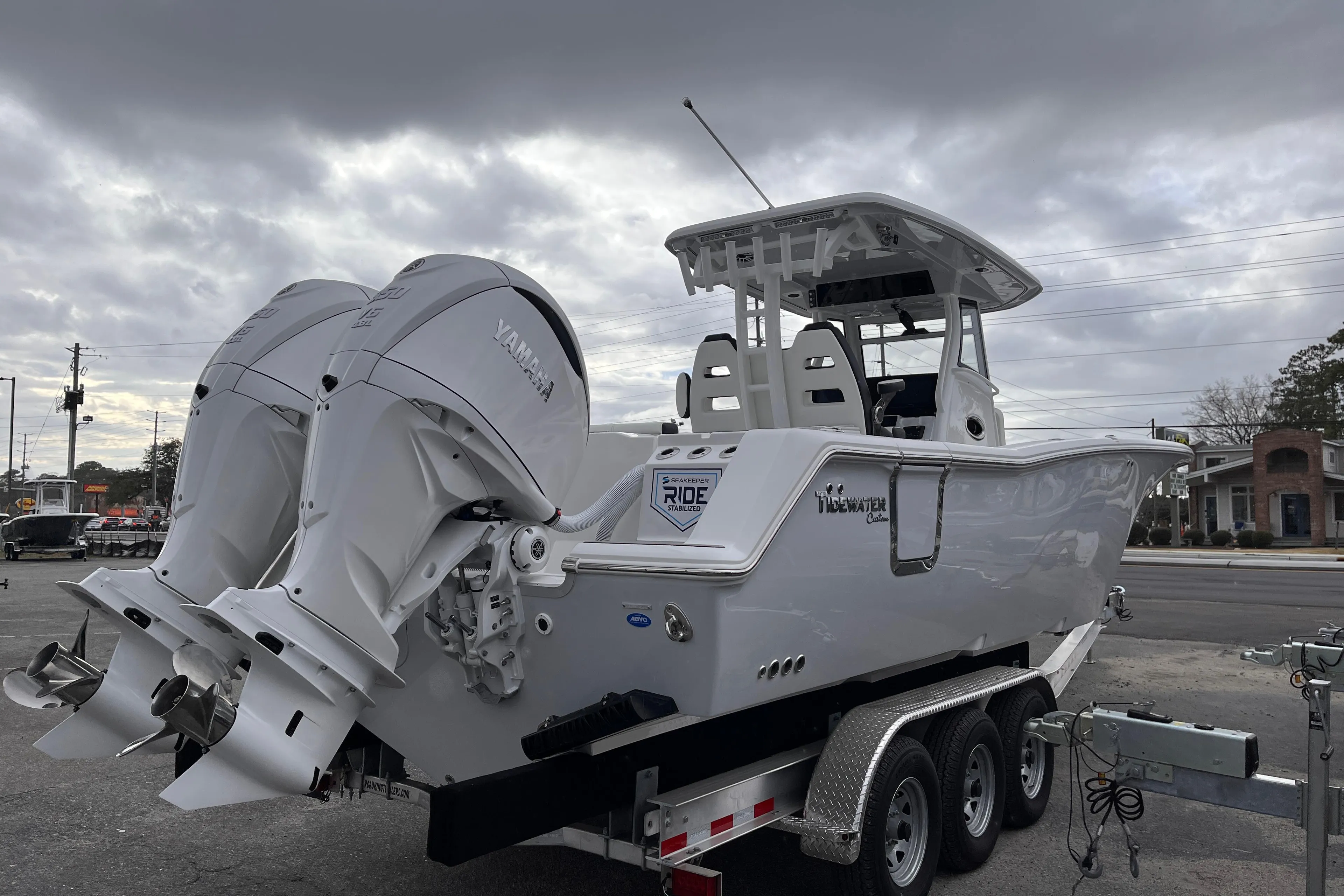 2025 Tidewater 302 CC Adventure boat on trailer, featuring dual engines, under cloudy sky.
