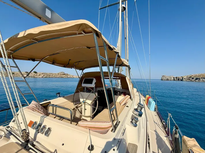  Yacht Photos Pics 2008 Island Packet 465 sailboat with tan canopy, anchored in clear blue waters.