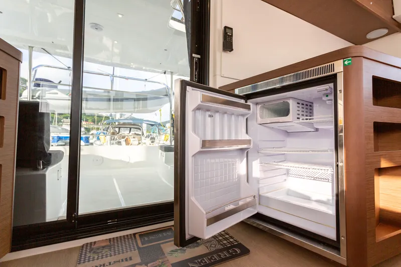Arctic Fantasy II Yacht Photos Pics Open refrigerator inside 2020 Lagoon 42 catamaran, with view of deck through glass door.