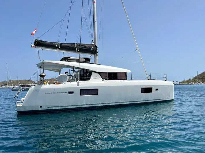 Arctic Fantasy II Yacht Photos Pics 2020 Lagoon 42 catamaran sailing on clear blue water, under a sunny sky.