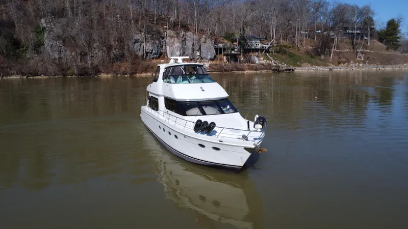  Yacht Photos Pics 2005 Carver 56 Voyager yacht on calm river with wooded shoreline.