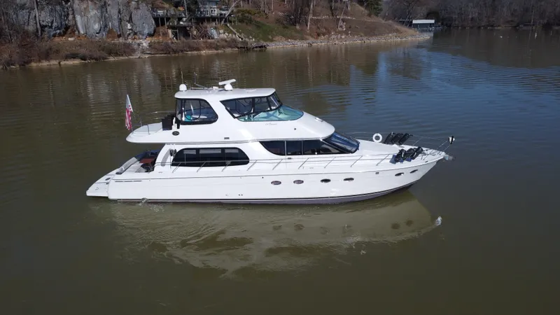  Yacht Photos Pics 2005 Carver 56 Voyager yacht on a calm lake, surrounded by rocky shoreline.