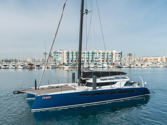 Flash Yacht Photos Pics 2017 HH Catamarans HH66 sailing in marina, sleek design, blue hull, modern waterfront backdrop.