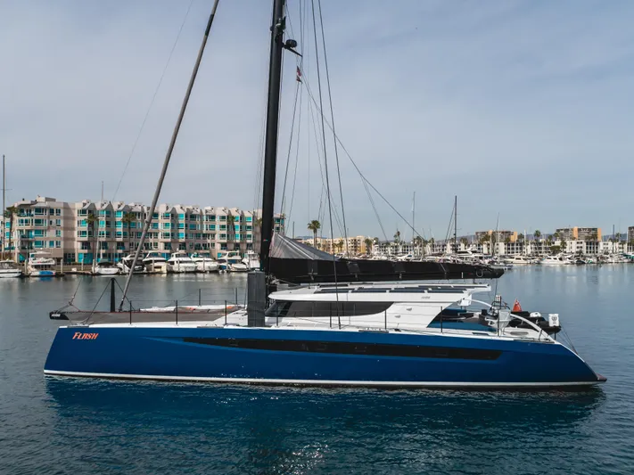 Flash Yacht Photos Pics 2017 HH Catamarans HH66 sailing in marina, sleek blue design, modern architecture in background.