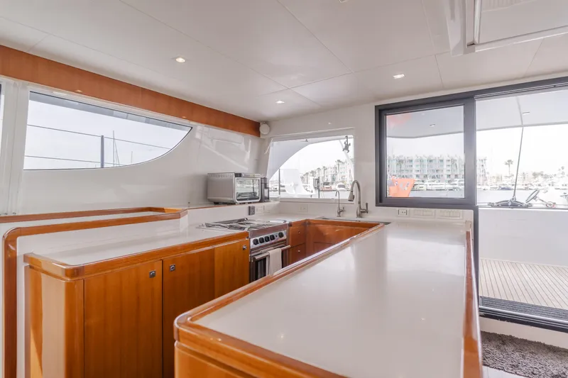 Flash Yacht Photos Pics Modern kitchen interior of 2017 HH Catamarans HH66 with wood cabinetry and large windows.