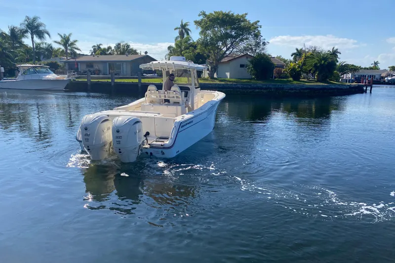  Yacht Photos Pics 2024 Grady-White Canyon 306 boat cruising on a sunny, palm-lined waterway.