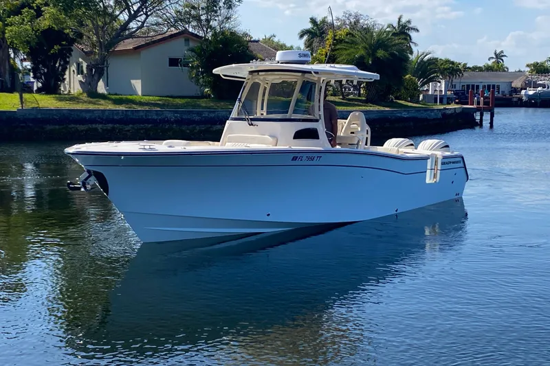  Yacht Photos Pics 2024 Grady-White Canyon 306 boat cruising on a calm waterway, surrounded by lush greenery.