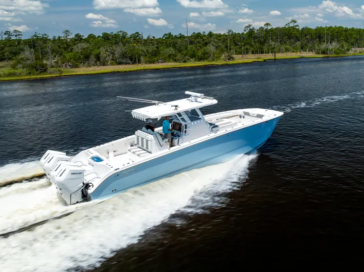  Yacht Photos Pics 2024 Invincible 37 Catamaran cruising on a scenic waterway under a clear sky.