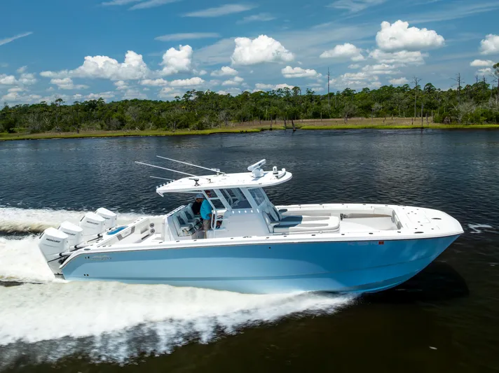  Yacht Photos Pics 2024 Invincible 37 Catamaran cruising on a scenic waterway under a clear blue sky.