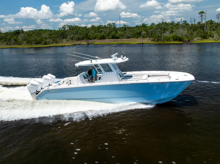  Yacht Photos Pics 2024 Invincible 37 Catamaran cruising on a scenic waterway under a clear sky.