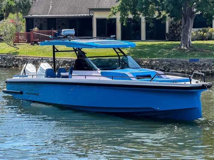 Yacht Photos Pics 2025 Axopar 37 Sun Top BRABUS Trim boat in vibrant blue on a calm waterway.