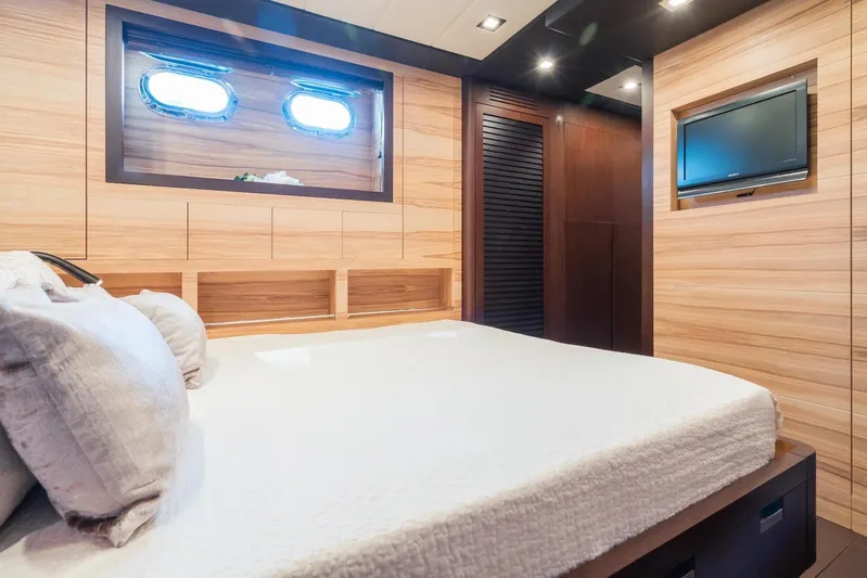 MilÙ II Yacht Photos Pics Luxurious bedroom interior on 2009 Overmarine Mangusta 80 yacht, featuring wood paneling and porthole windows.