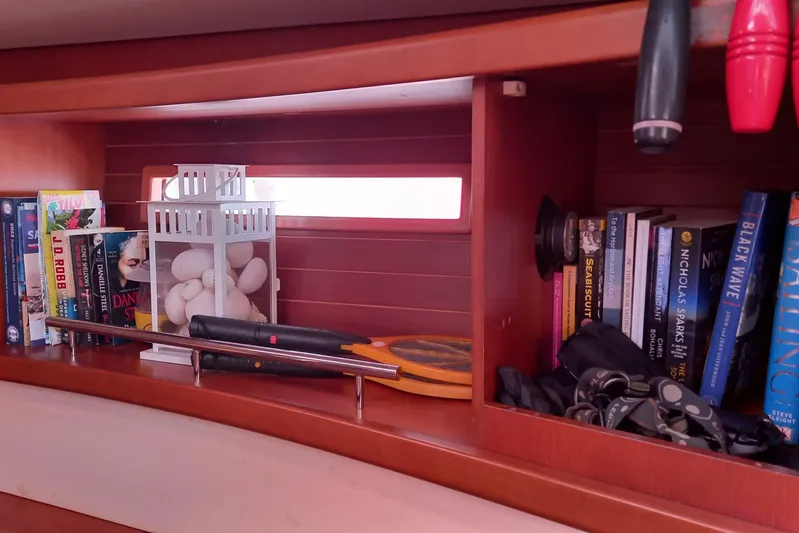 We Reach Yacht Photos Pics Bookshelf on 2011 Dufour 425 Grand Large yacht with books, tools, and decor.