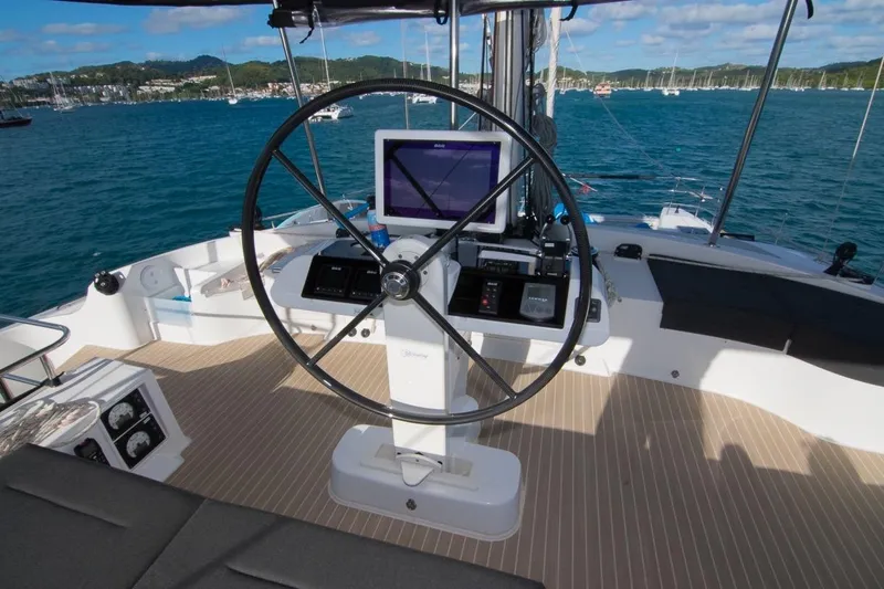 Oui Cherie Yacht Photos Pics Helm of 2017 Lagoon 52 F catamaran with navigation equipment, overlooking a scenic marina.