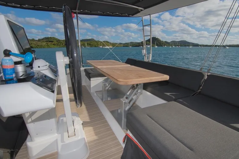 Oui Cherie Yacht Photos Pics 2017 Lagoon 52 F yacht cockpit with seating, table, and steering wheel, overlooking scenic water view.
