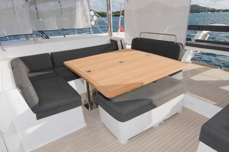 Oui Cherie Yacht Photos Pics Outdoor seating area on 2017 Lagoon 52 F yacht with wooden table and cushioned benches.