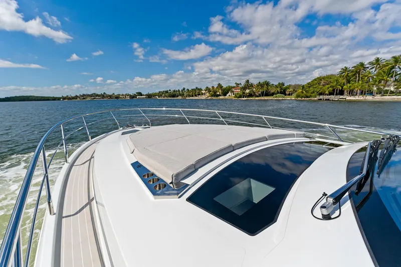  Yacht Photos Pics 2024 Uniesse Exuma HTC5p yacht cruising on a sunny day near a tropical shoreline.