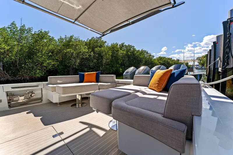  Yacht Photos Pics 2024 Uniesse Exuma HTC5p yacht deck with modern seating and canopy, surrounded by lush greenery.
