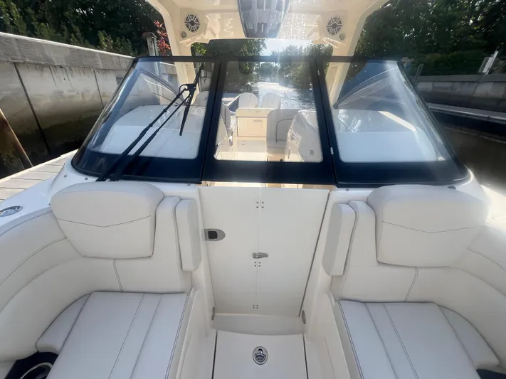  Yacht Photos Pics 2025 Scout 277 Dorado boat interior with white seating and windshield, docked by a canal.