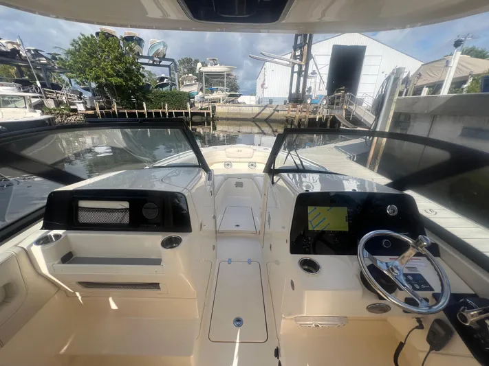  Yacht Photos Pics 2025 Scout 277 Dorado boat interior with steering wheel and navigation system at a marina.