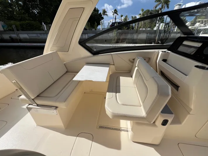  Yacht Photos Pics 2025 Scout 277 Dorado boat interior with beige seating and table, dockside view.