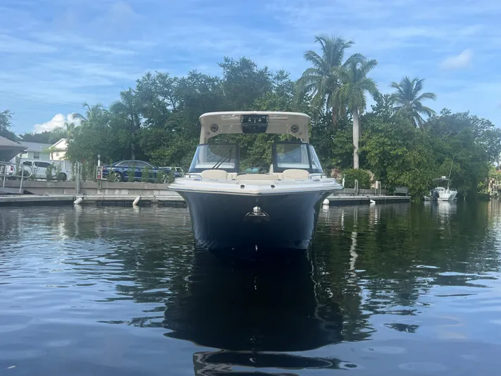  Yacht Photos Pics 2025 Scout 277 Dorado boat docked on calm water, surrounded by lush greenery.